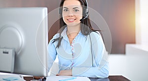 Young brunette business woman looks like a student girl working in office. Hispanic or latin american girl talking by