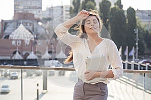 Young brunette business woman in white skirt and grey suit trousers chilling, relaxing after hard day at work. European city on