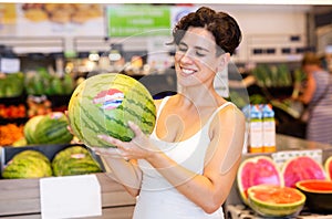 Young brunette choosing ripe sweet watermelon supermarket