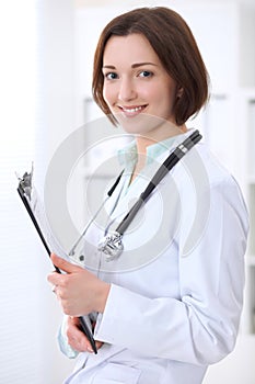 Young brunette female doctor standing with arms crossed and smiling at hospital