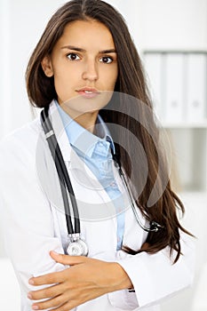 Young brunette female doctor standing and smiling at hospital