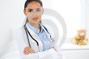 Young brunette female doctor standing and smiling at hospital