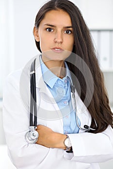 Young brunette female doctor standing and smiling at hospital