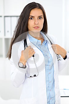 Young brunette female doctor standing and smiling at hospital