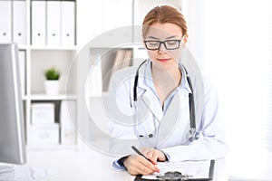 Young brunette female doctor at work in hospital. Physician ready to help. Medicine and healthcare concept