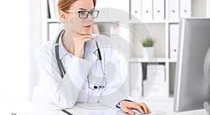 Young brunette female doctor at work in hospital. Physician ready to help. Medicine and healthcare concept