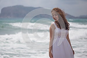 Young brunette female with wavy hair wearing white dress photo