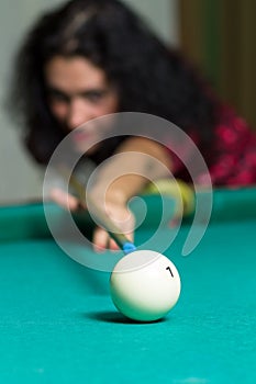 Young brunette girl aiming to ball playing billiard game