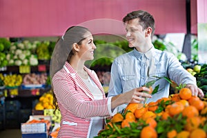 Young brunette girl and boyfriend buying citruses i