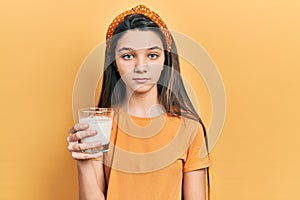 Young brunette girl drinking a glass of milk thinking attitude and sober expression looking self confident