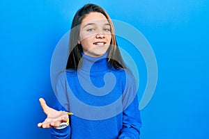 Young brunette girl wearing turtleneck sweater smiling cheerful with open arms as friendly welcome, positive and confident