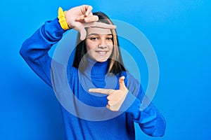 Young brunette girl wearing turtleneck sweater smiling making frame with hands and fingers with happy face