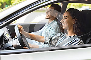 Young brunette lady driving car, having car trip with husband