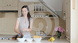 A young brunette lays out fruit from an eco-basket herself in the kitchen.