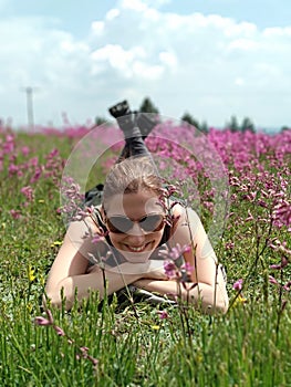 Young brunette lying on the grass among the flowers facing the camera.