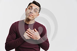 Young brunette man holding hands in his chest and looking at camera