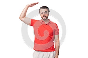 young brunette man in a red corporate t-shirt on a white background with copy space