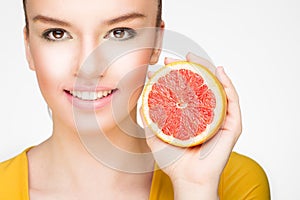 Young brunette with red grapefruit in her hand