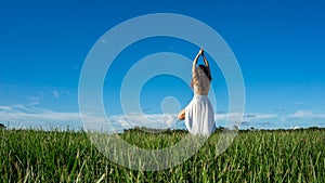 Young brunette spanish woman doing Vriksasana tree yoga pose in a field next to a lake with long curly hair Space in sky