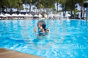 Young brunette teen girl posing in a blue swimming pool in a hotel in Turkey