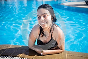 Young brunette teen girl posing in a blue swimming pool in a hotel in Turkey