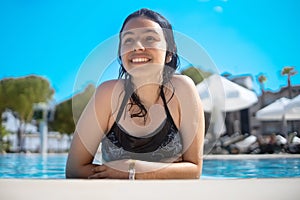 Young brunette teen girl posing in a blue swimming pool in a hotel in Turkey