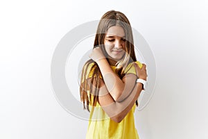 Young brunette teenager standing together over isolated background hugging oneself happy and positive, smiling confident