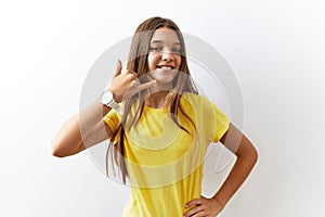 Young brunette teenager standing together over isolated background smiling doing phone gesture with hand and fingers like talking