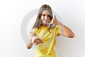 Young brunette teenager standing together over isolated background smiling doing talking on the telephone gesture and pointing to