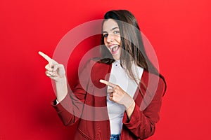 Young brunette teenager wearing business jacket smiling and looking at the camera pointing with two hands and fingers to the side