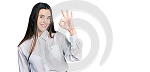 Young brunette teenager wearing business white shirt smiling positive doing ok sign with hand and fingers