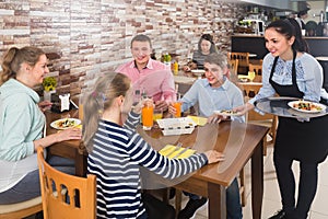 Young brunette waitress serving family in family cafe