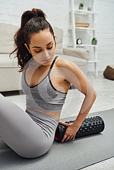 Young brunette woman in activewear holding