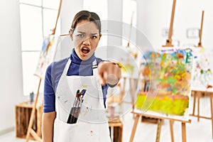 Young brunette woman at art studio pointing displeased and frustrated to the camera, angry and furious with you