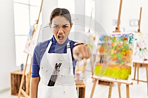 Young brunette woman at art studio pointing displeased and frustrated to the camera, angry and furious with you