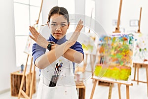 Young brunette woman at art studio rejection expression crossing arms doing negative sign, angry face