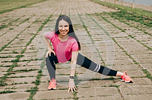 Young brunette woman with bare feet  wearing black and purple fitness outfit  stretching on violet yoga mat outside on wooden pier photo