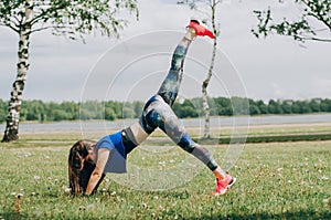 Young brunette woman with bare feet  wearing black and purple fitness outfit  stretching on violet yoga mat outside on wooden pier photo