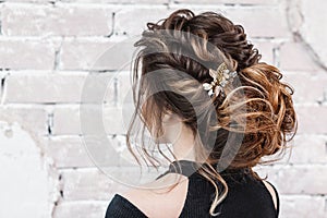 Young brunette woman with beautiful hairstyle with hair detail accessory, closeup rear view