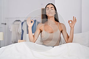 Young brunette woman in the bed at home relax and smiling with eyes closed doing meditation gesture with fingers