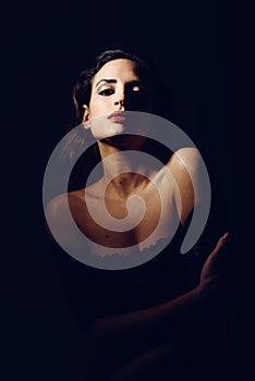 Young brunette woman in black lingerie in chiaroscuro lighting