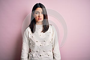 Young brunette woman with blue eyes wearing casual sweater over isolated pink background depressed and worry for distress, crying