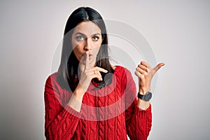 Young brunette woman with blue eyes wearing casual sweater over isolated white background asking to be quiet with finger on lips