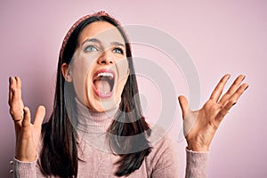 Young brunette woman with blue eyes wearing casual t-shirt and diadem crazy and mad shouting and yelling with aggressive