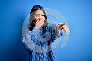 Young brunette woman with blue eyes wearing casual turtleneck sweater laughing at you, pointing finger to the camera with hand