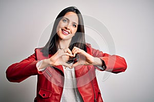 Young brunette woman with blue eyes wearing red casual jacket over white background smiling in love showing heart symbol and shape