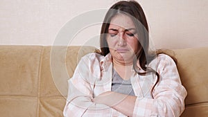 Young brunette woman crying sitting on the sofa