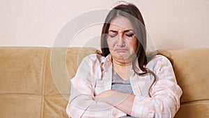 Young brunette woman crying sitting on the sofa