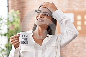 Young brunette woman drinking from i am the boss coffee cup stressed and frustrated with hand on head, surprised and angry face