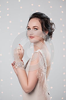 Young brunette woman in evening dress on a white background. Holding Christmas present box. Joy, happiness and surprise.